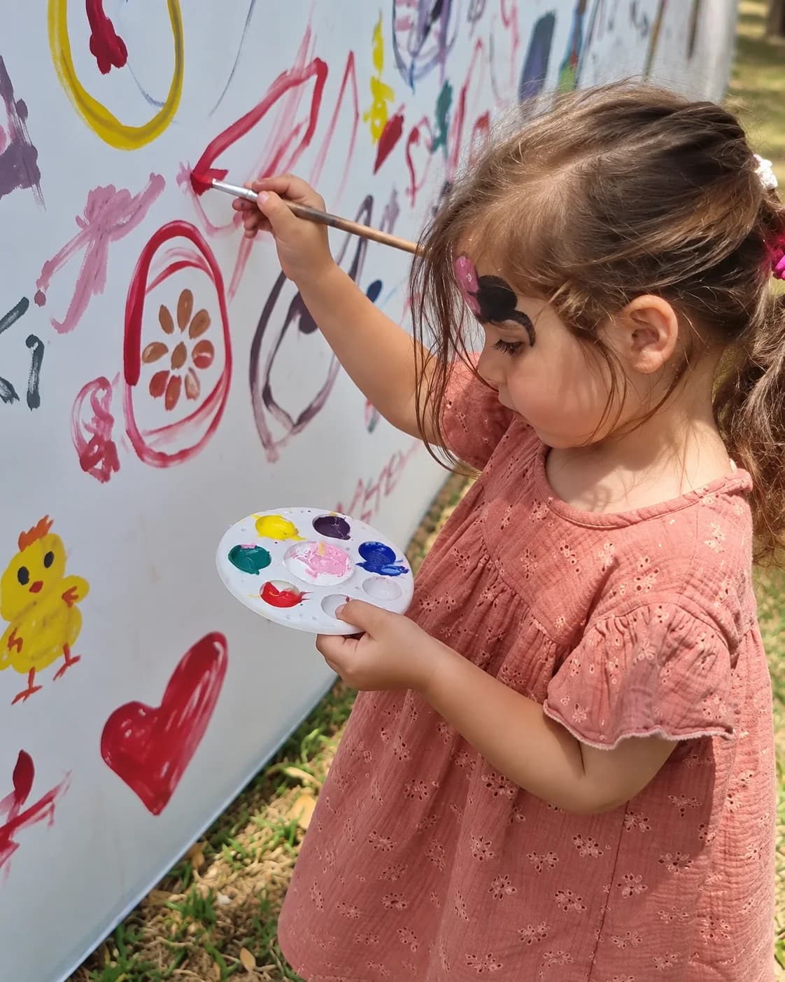 ילדה אוחזת במכחול ובפלטה ומציירת על הקיר