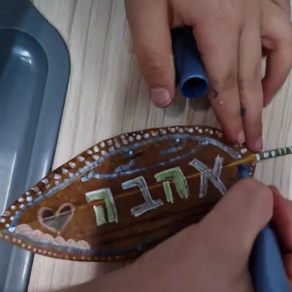 ידיים מוסיפות פרטים צבעוניים על עלה מצויר